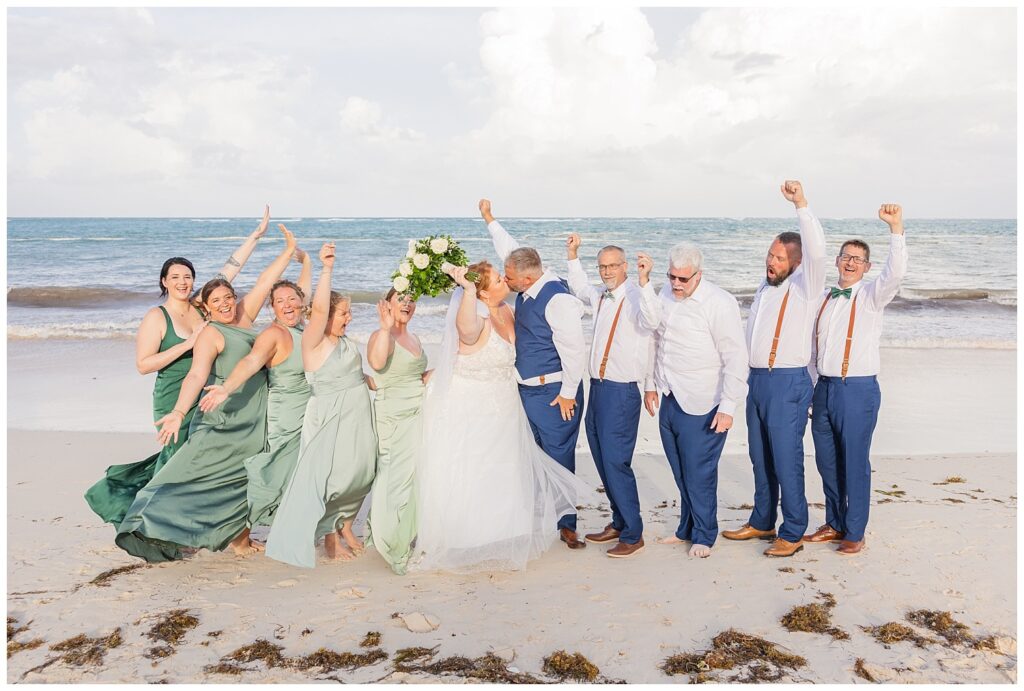 full wedding party posing together on the beach at the ocean at Punta Cana Dreams Resort
