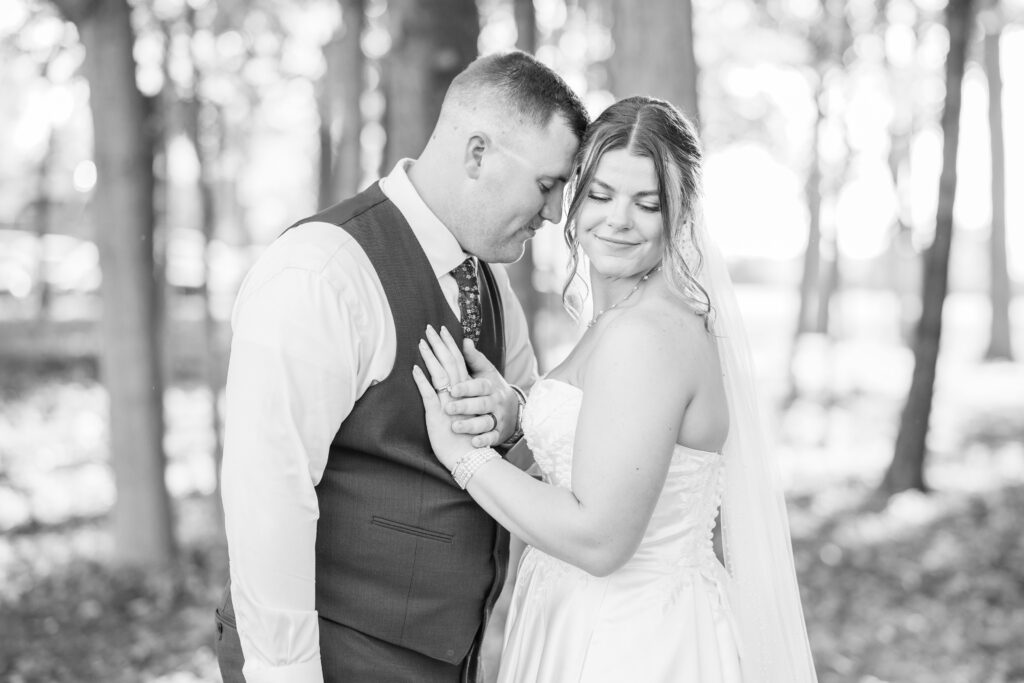 bride and groom holding hands on the groom's chest while posing outside at Tiffin, Ohio wedding