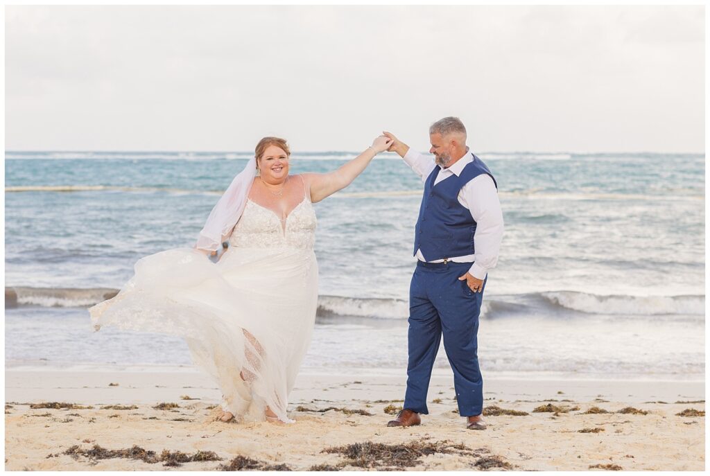 groom twirling the bride on the beach for their wedding celebration at Punta Cana Dream Resort