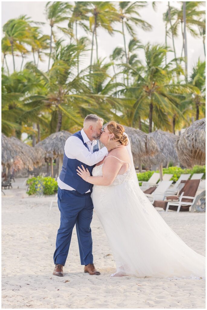 bride and groom sharing a kiss on the beach among palm trees for fall destination wedding in Punta Cana