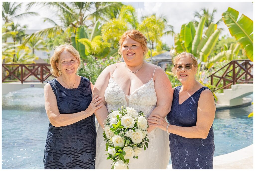 bride posing with both her mom and the groom's mom near the pools in Punta Cana