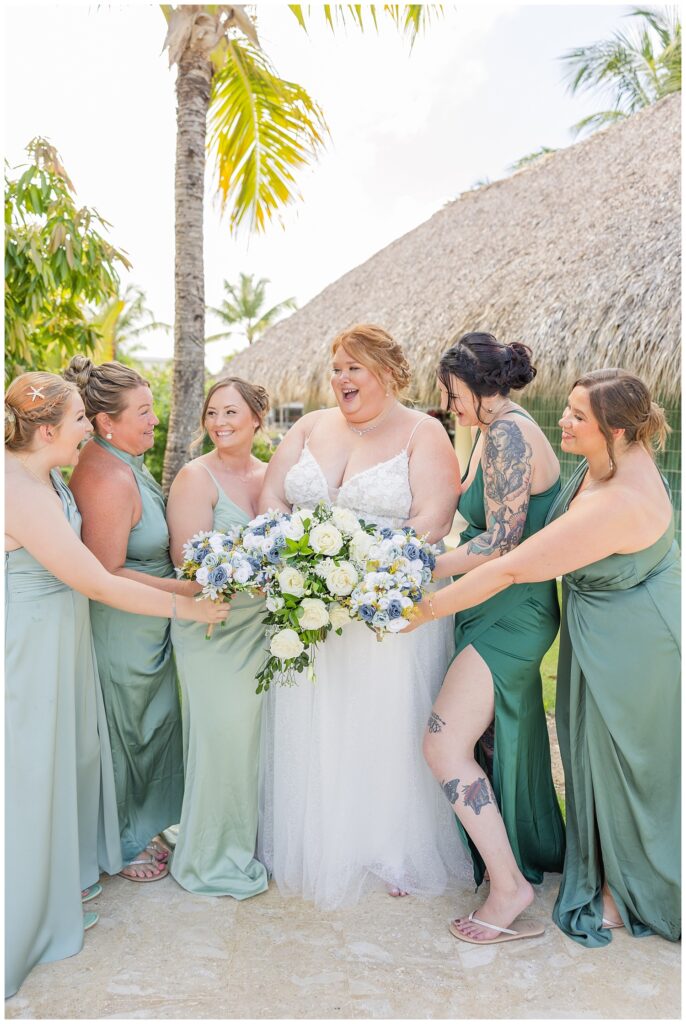 bride and bridesmaids putting their flowers in the middle and laughing together