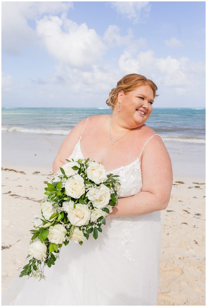 bride tilting back while holding the bouquet on the beach for Punta Cana destination wedding in the sun