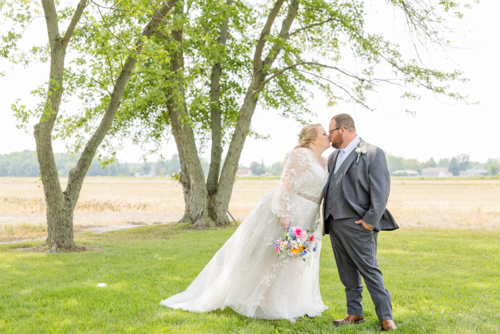 bride and groom sharing a kiss near a field and trees in Tiffin, Ohio