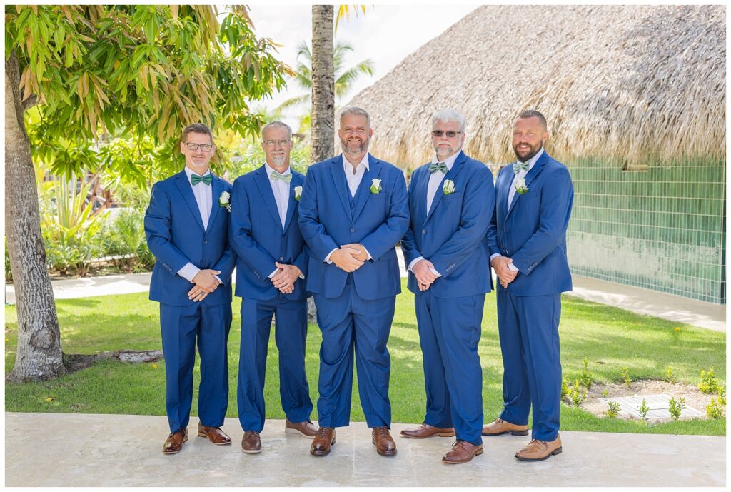 groom posing with groomsmen near the pools under the palm trees at Punta Cana wedding
