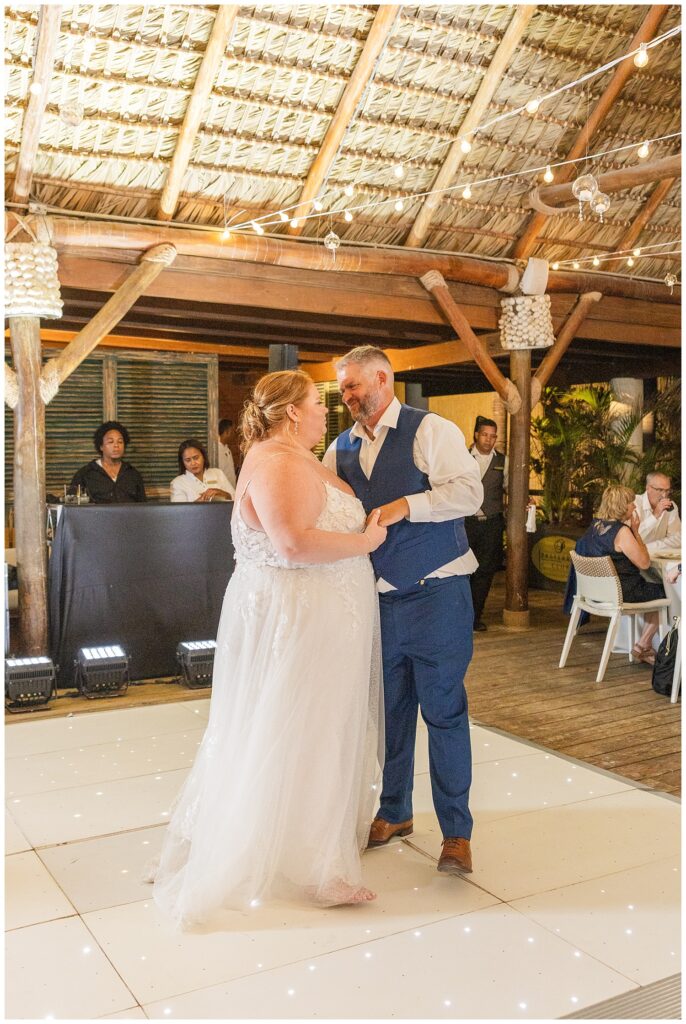 bride and groom having their first official dance on the floor while guests enjoy their drinks