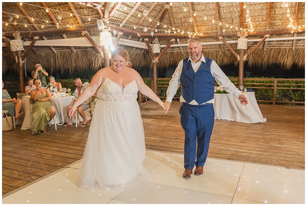 bride and groom having their first official dance on the floor while guests enjoy their drinks