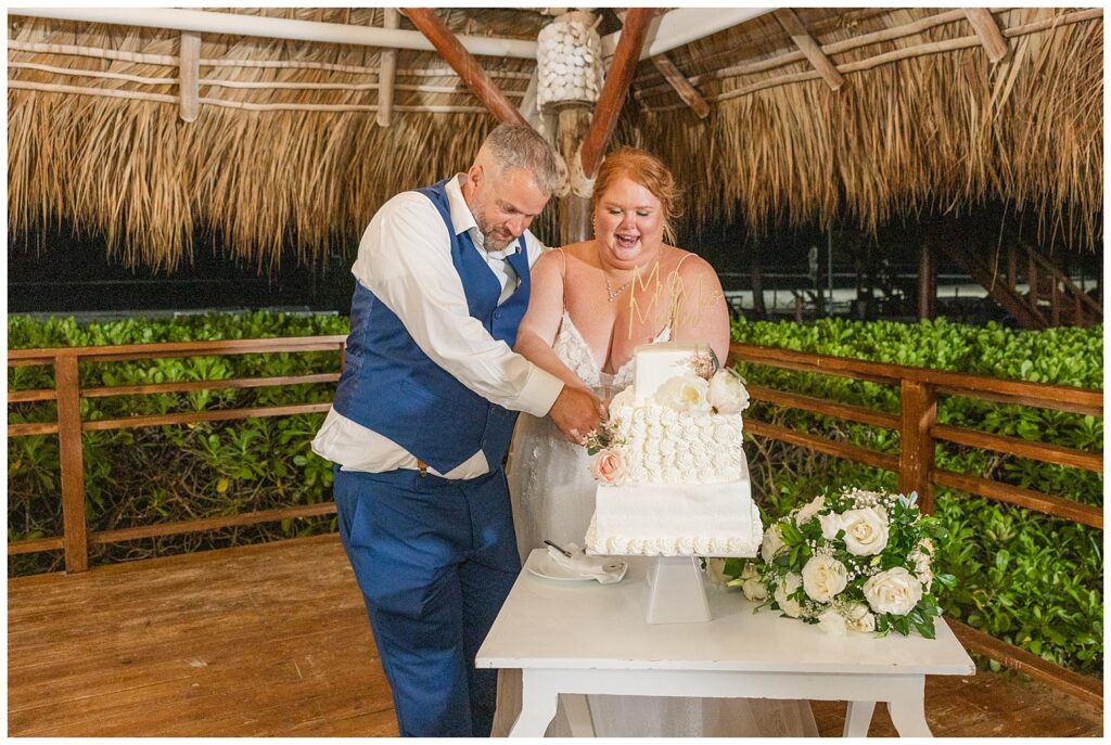 wedding couple cutting their cake on white table at Punta Cana wedding reception