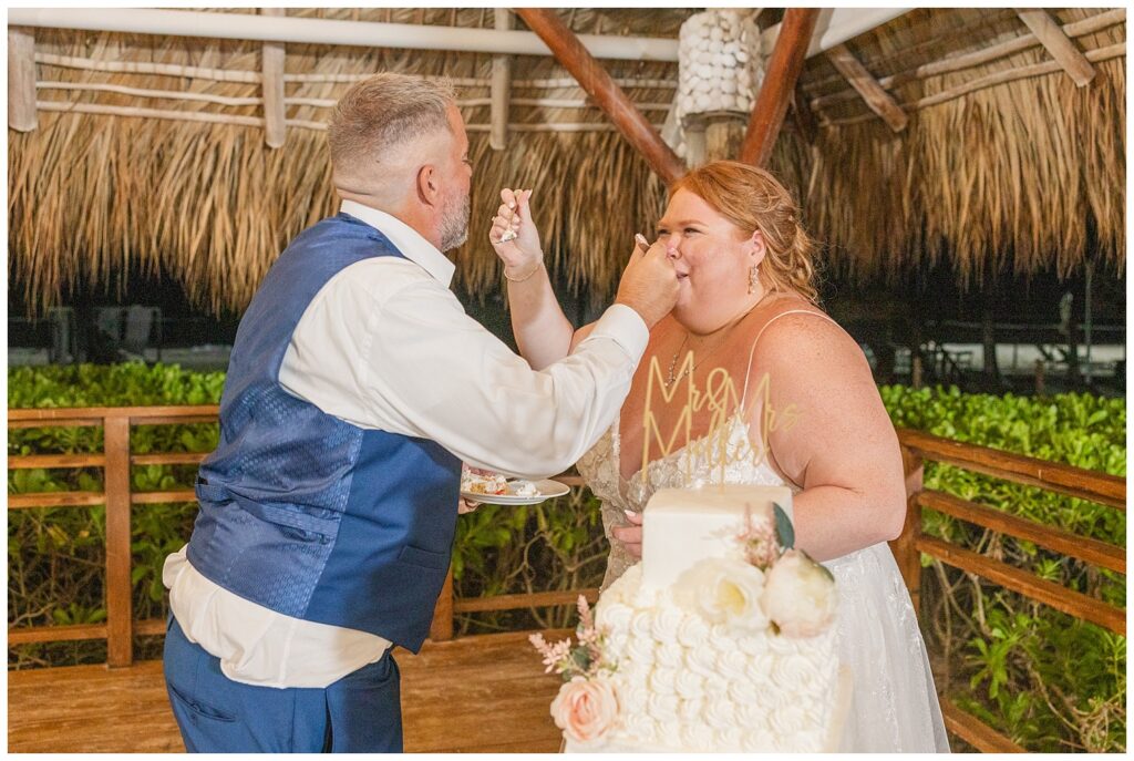 wedding couple feeding each other cake on white table at Punta Cana wedding reception