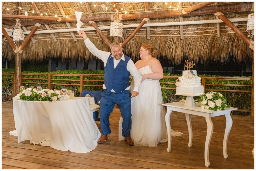 bride and groom cheering after cutting their cake at Punta Cana fall wedding reception