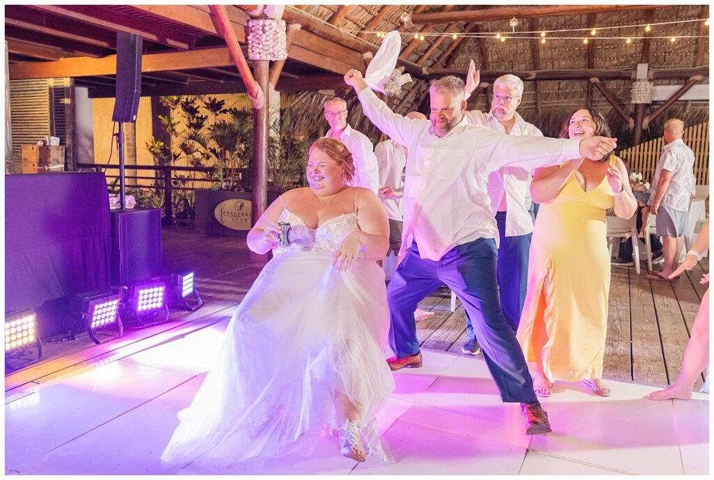 groom dancing around the bride before he takes her garter off at Punta Cana wedding reception