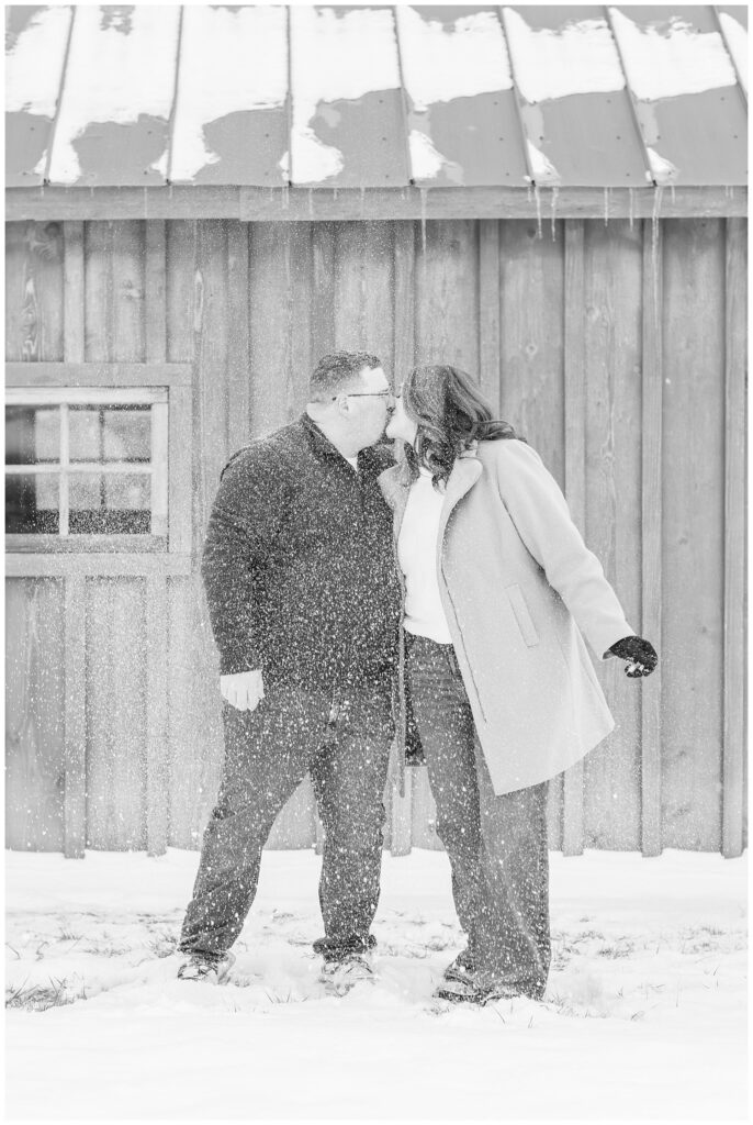 engaged couple kissing after throwing snow in the air with Bloomville, OH portrait photographer
