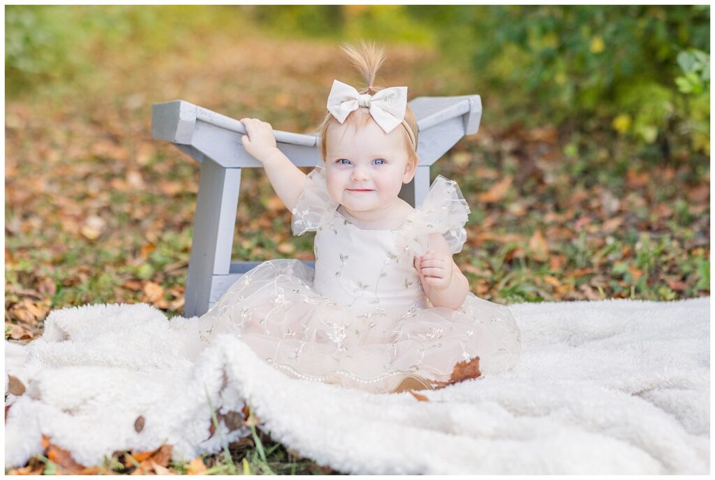little girl wearing a light pink dress and sitting on a blanket for cake smash