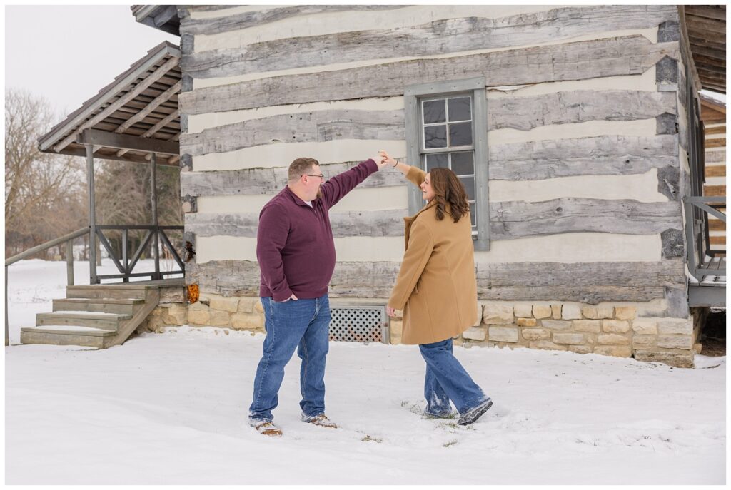 couple twirling in the snow at log cabin with Bloomville, OH engagement photographer
