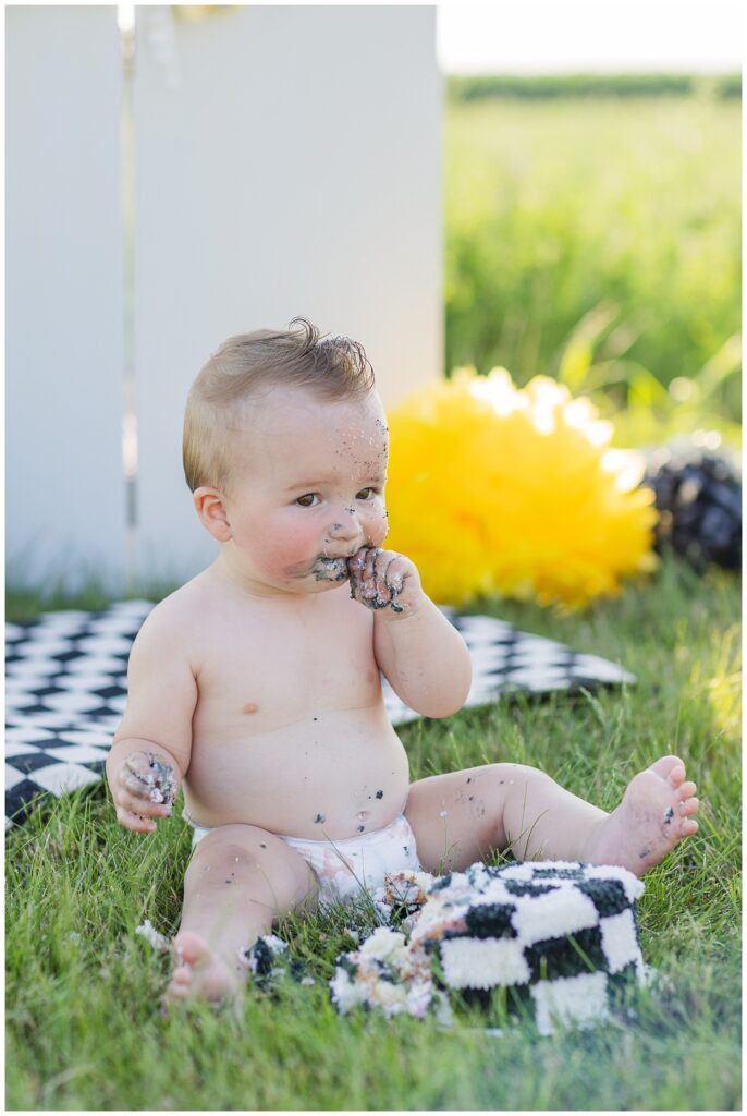 one year old eating a black and white smash cake while wearing a diaper