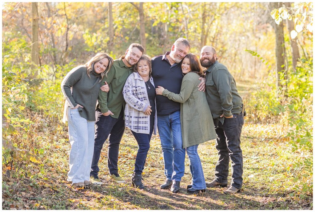 parents and their four grown children posing on a walking path in the woods for extended family session