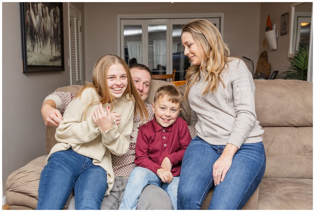family of four laughing on the couch for in-home extended session with Tiffin, OH photographer