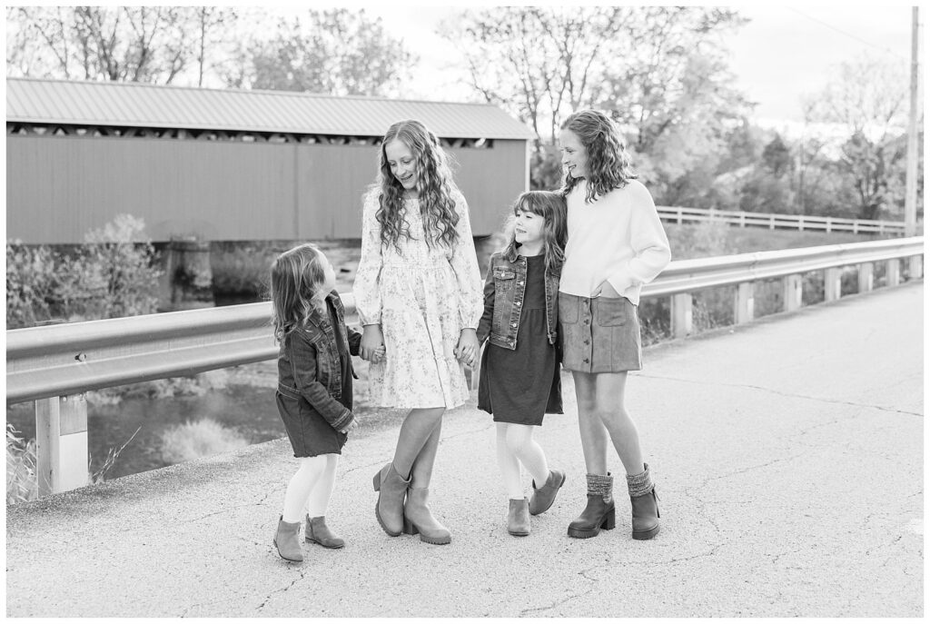 four girl cousins posing on the road near a red bridge at extended family session