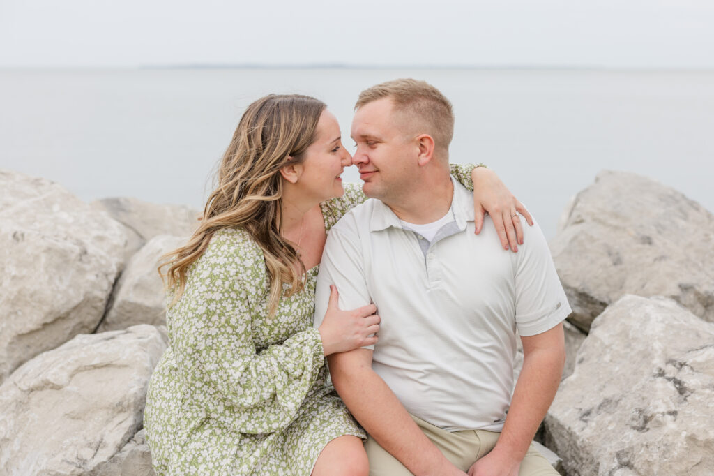 engaged couple sitting on the rocks at Lake Erie at East Harbor State Park
