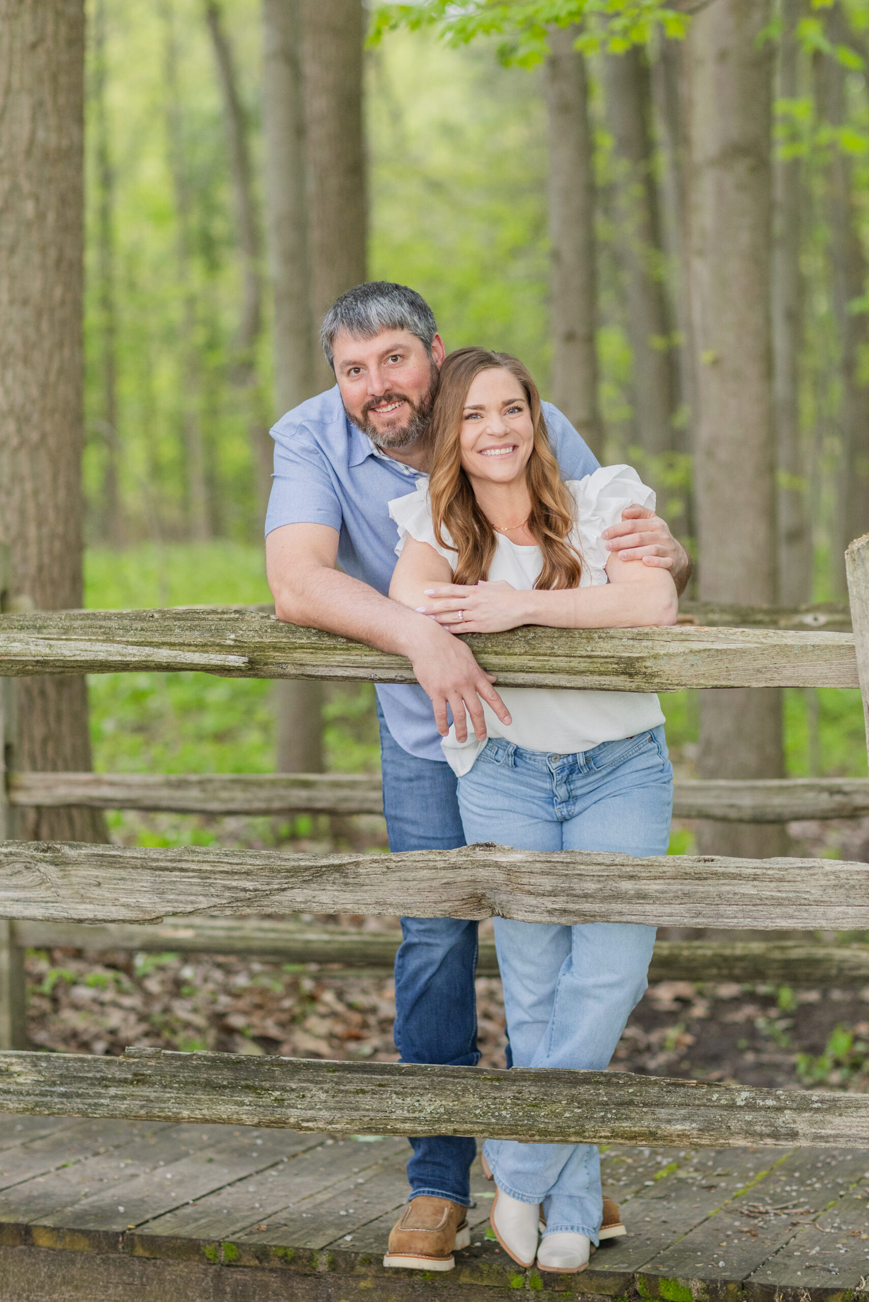 engaged couple leaning against a fence on groom's farm in Bradner, Ohio