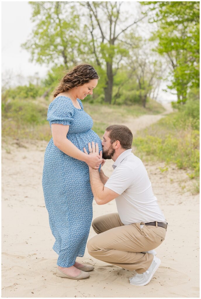 husband kissing his wife's pregnant belly during maternity session at East Harbor State Park