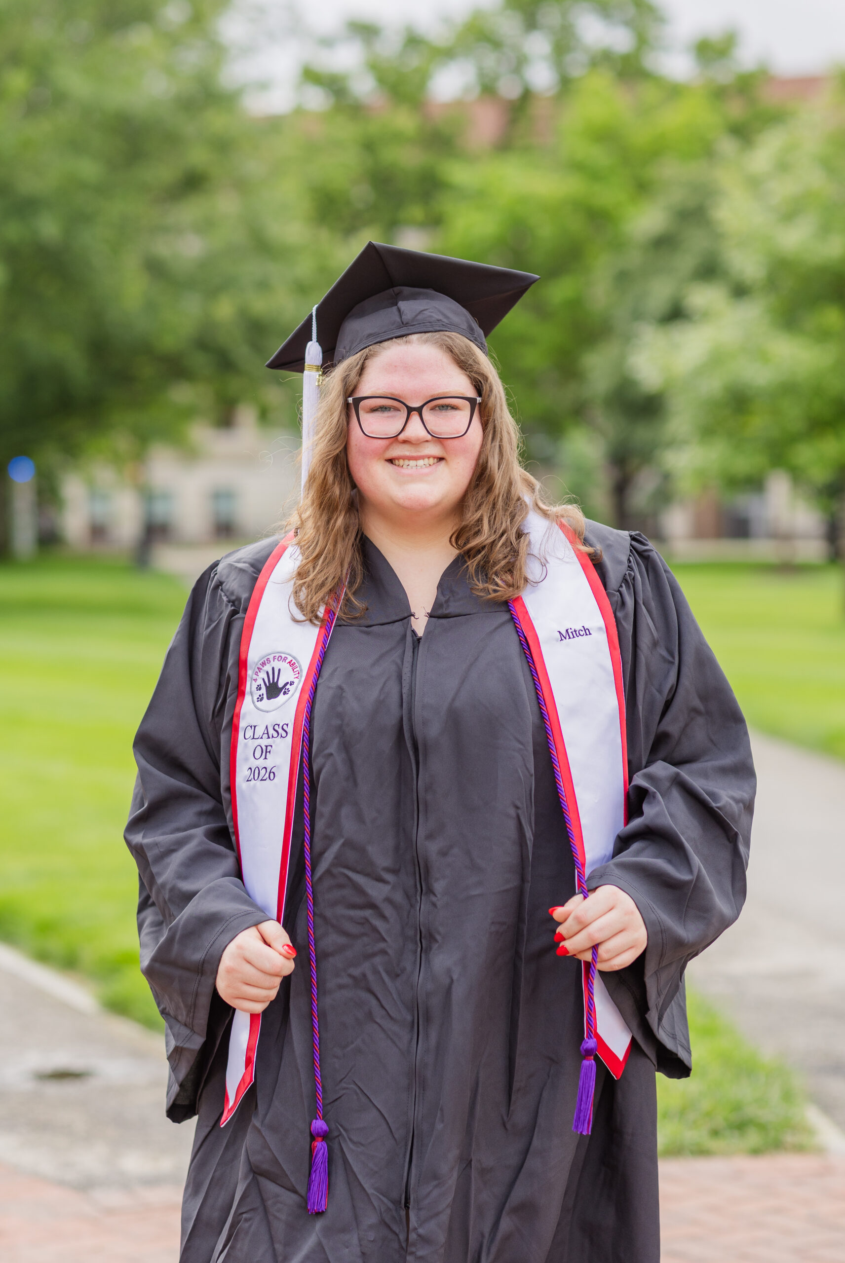 college graduate posing with her cap and gown at Ohio State University campus
